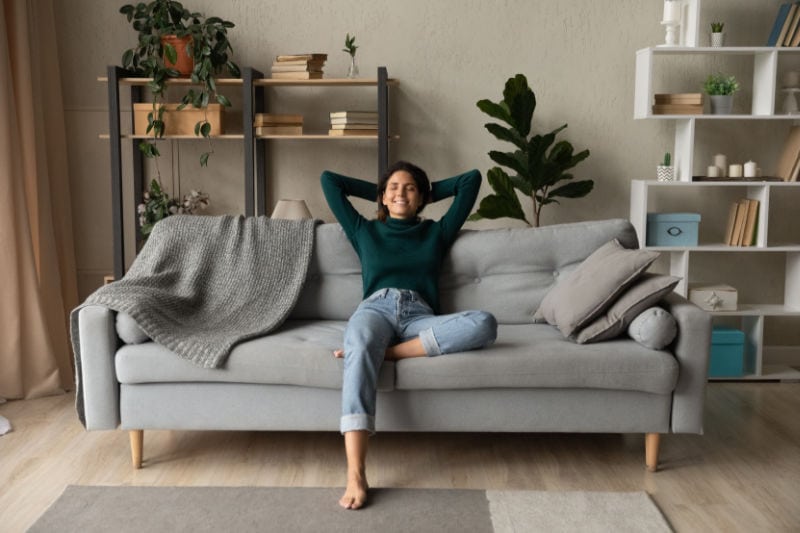 Signs I Need a New Furnace. Woman sitting comfortably on the couch in her home.